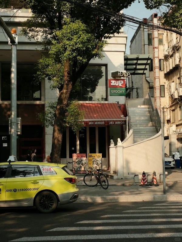 Cảnh đường phố nhìn từ trên cao với những hàng cây xanh mướt và con đường uốn lượn, mang đến khoảnh khắc thư giãn.
