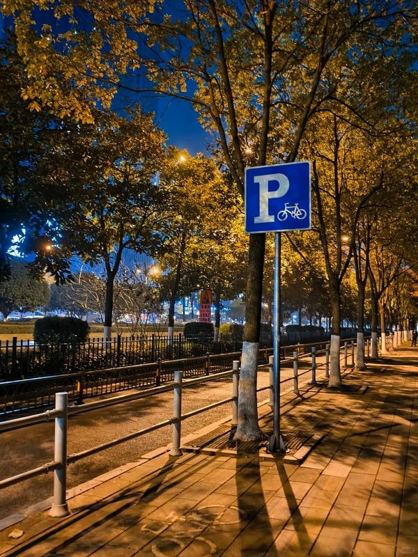 Hình ảnh một người đang đi bộ trên đường phố vào ban đêm, ánh đèn đường tạo nên bóng đổ dài, thể hiện vẻ đẹp đường phố yên bình.